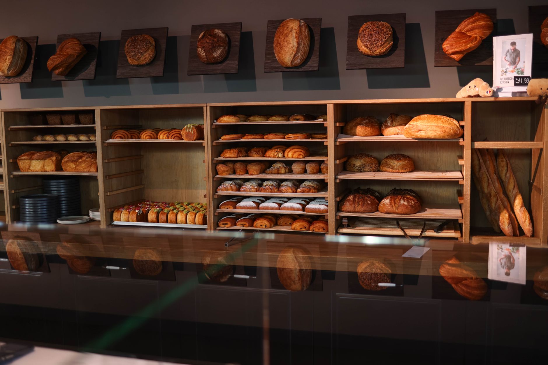 Intérieur chaleureux d'une boulangerie artisanale avec des pains et des viennoiseries dorées sur des étagères en bois